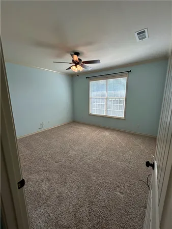 an empty room with windows and chandelier fan