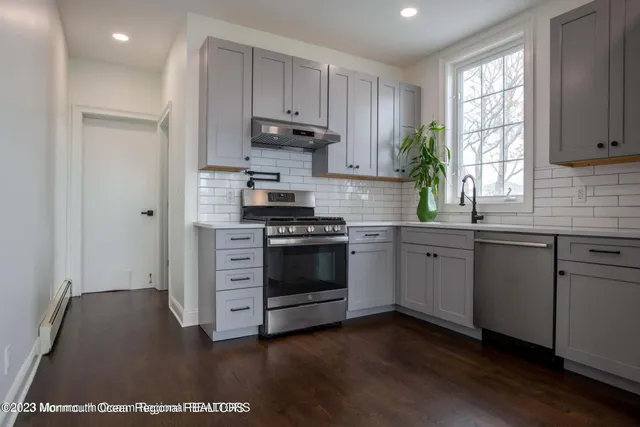 a kitchen with stainless steel appliances a white stove top oven cabinets and a window
