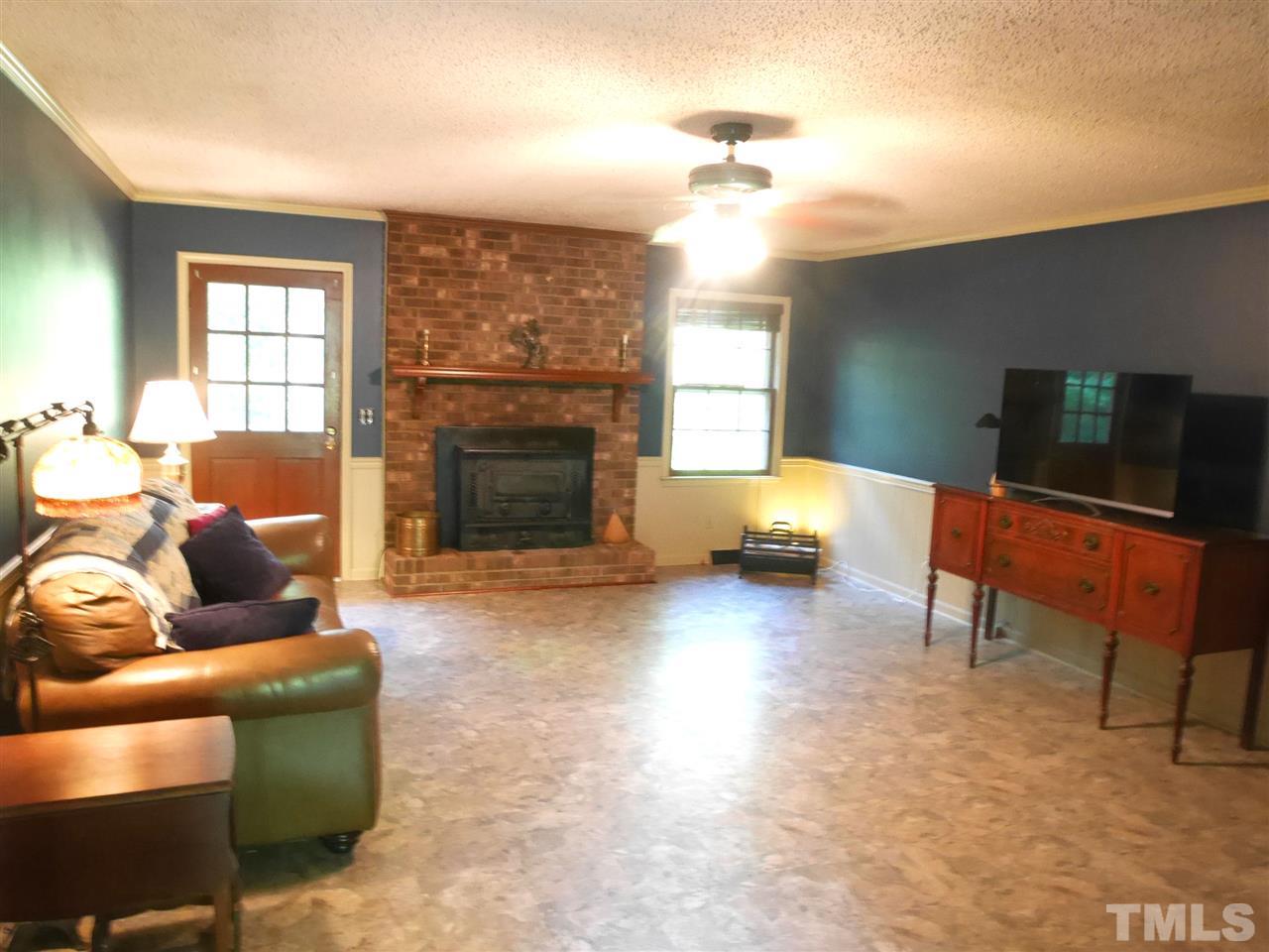 12701 Adams Drive Raleigh, NC 27603 - Photo 4 of 21 Wood Stove and brick fireplace is the center of the Living Room. Walk out to back deck