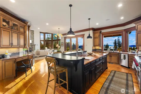 a large kitchen with stainless steel appliances granite countertop a stove and a view of living room