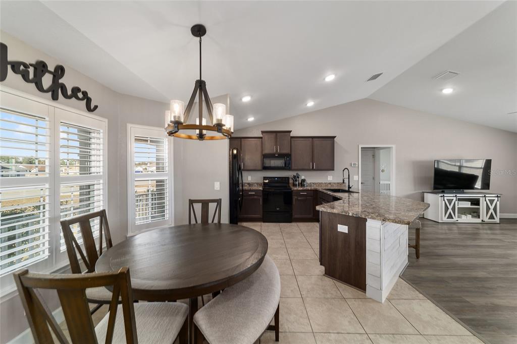 9155 Southeast 47th Court Road Ocala, FL 34480 - Photo 12 of 47 a kitchen with stainless steel appliances kitchen island granite countertop a refrigerator a stove a microwave oven a dining table and chairs