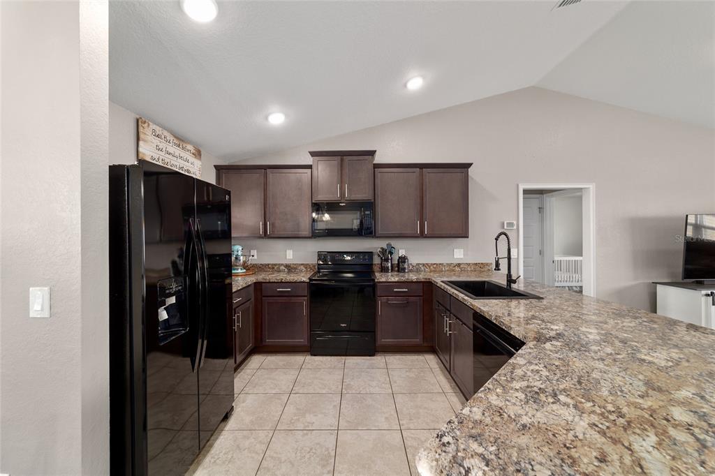 9155 Southeast 47th Court Road Ocala, FL 34480 - Photo 15 of 47 a kitchen with stainless steel appliances granite countertop a refrigerator stove top oven and a sink