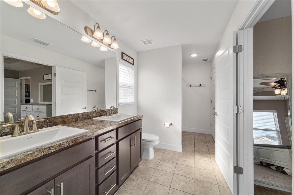 9155 Southeast 47th Court Road Ocala, FL 34480 - Photo 28 of 47 a bathroom with a granite countertop sink a toilet a large mirror a vanity and shower