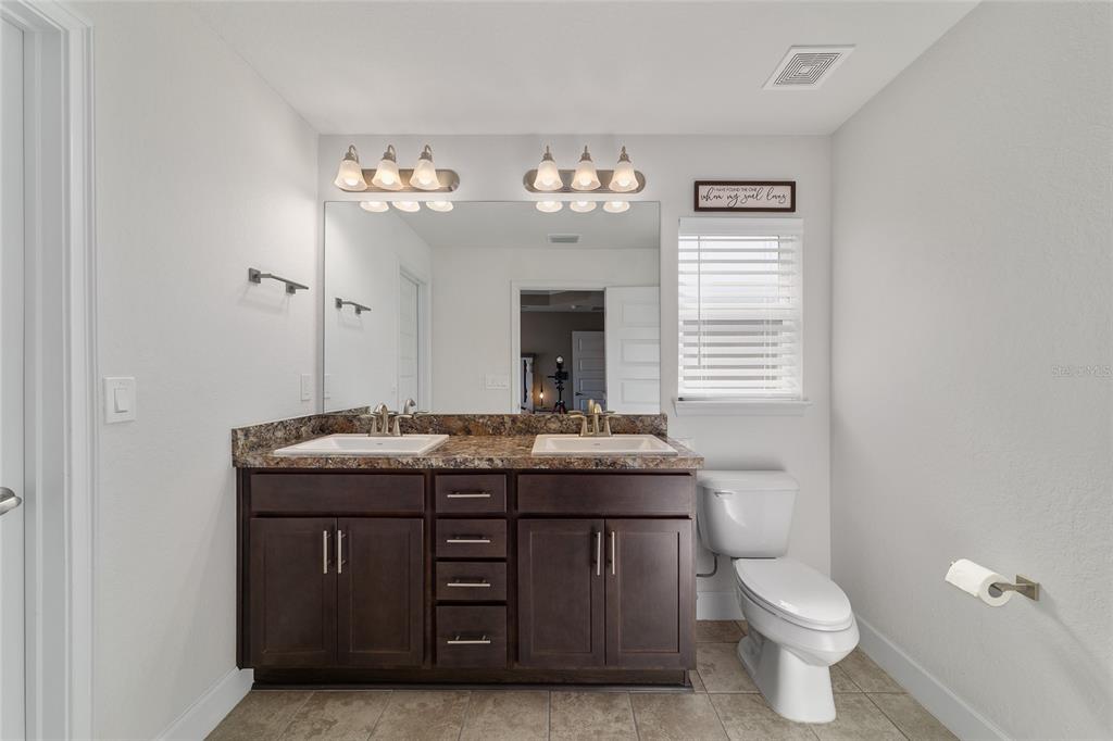 9155 Southeast 47th Court Road Ocala, FL 34480 - Photo 29 of 47 a bathroom with a granite countertop sink a toilet and a mirror