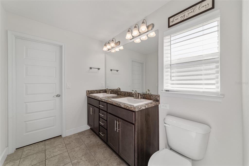 9155 Southeast 47th Court Road Ocala, FL 34480 - Photo 30 of 47 a bathroom with a granite countertop toilet sink and mirror