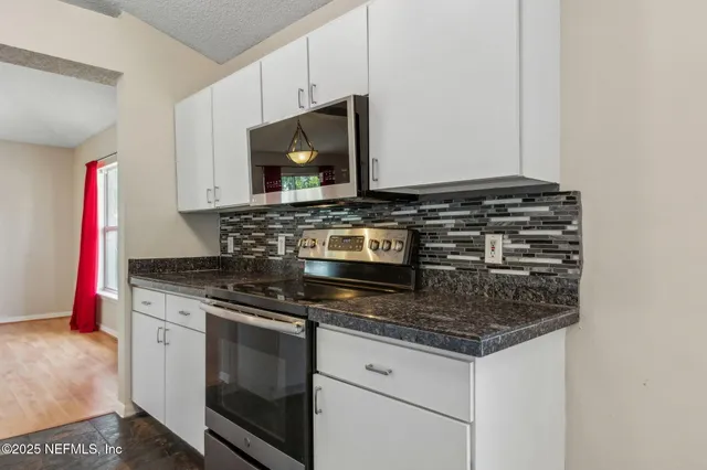 a kitchen with granite countertop a stove and a microwave