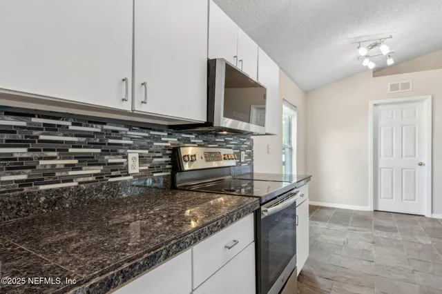 a kitchen with granite countertop a sink and a stove