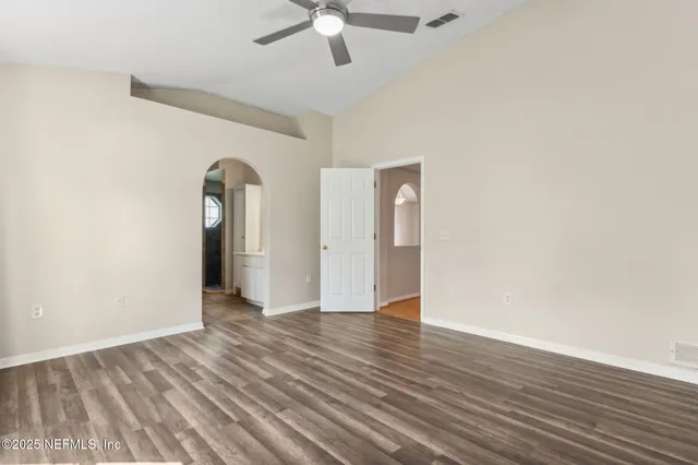an empty room with wooden floor chandelier fan and windows
