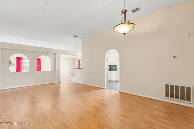a view of an empty room with wooden floor and windows
