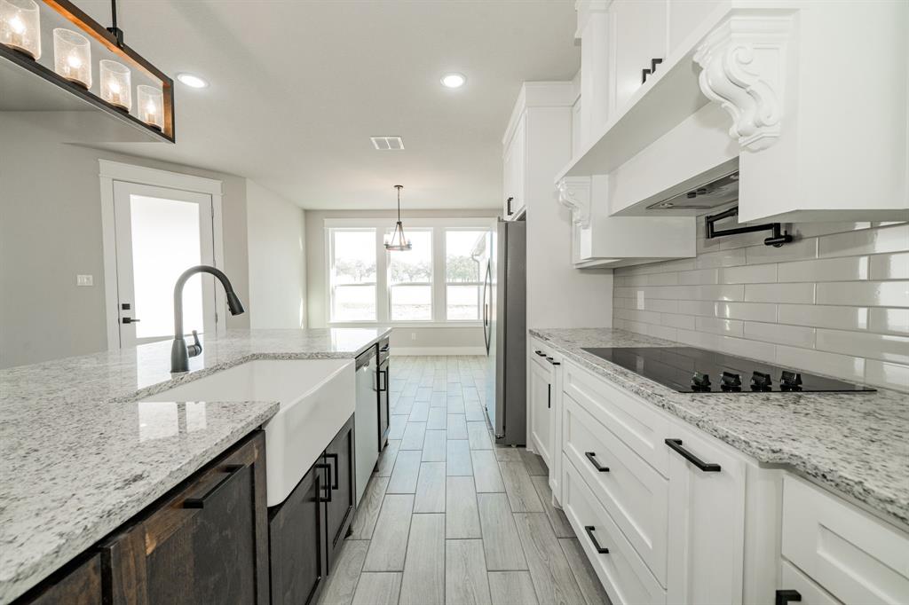 2017 Swallowtail Court Poolville, TX 76487 - Photo 15 of 32 a kitchen with granite countertop a sink and a stove
