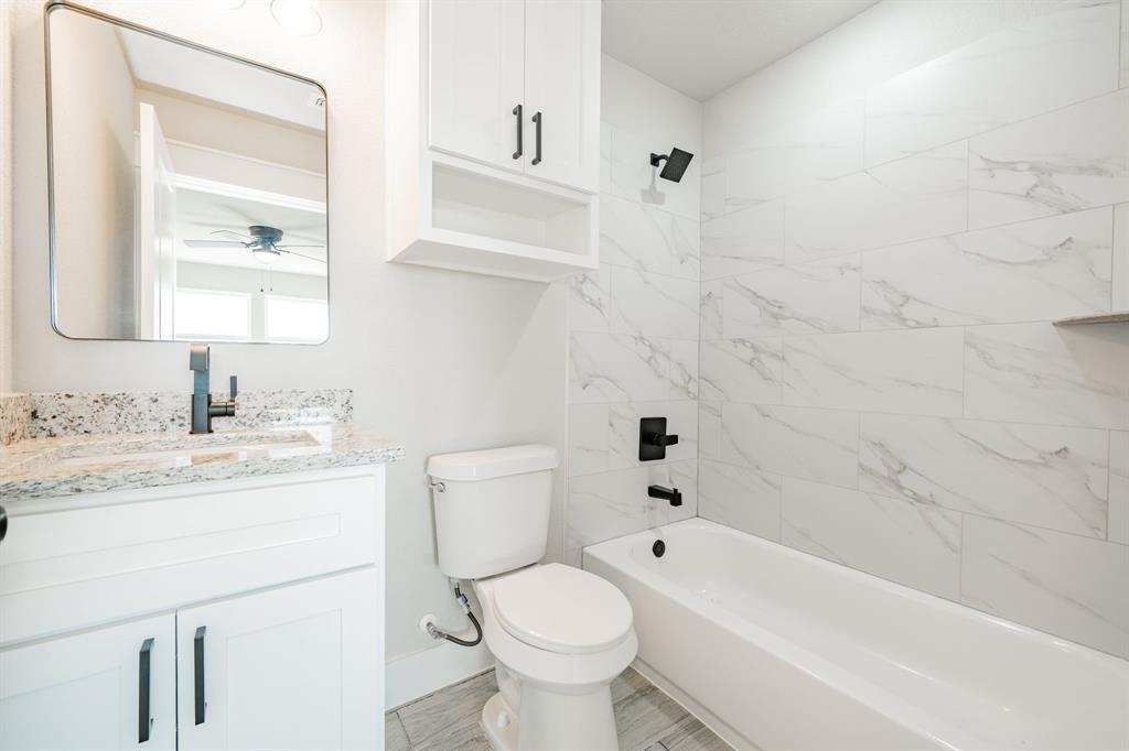 2017 Swallowtail Court Poolville, TX 76487 - Photo 27 of 32 a bathroom with a granite countertop toilet a sink and a bathtub