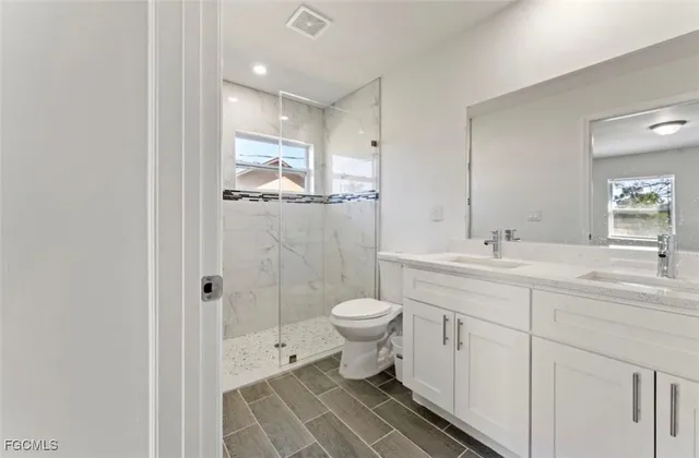 a bathroom with a double vanity sink mirror and toilet