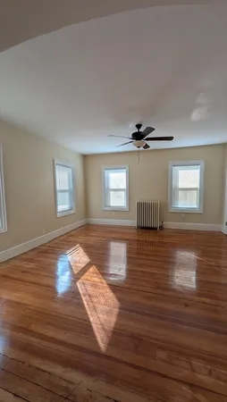 a view of empty room with wooden floor and fan
