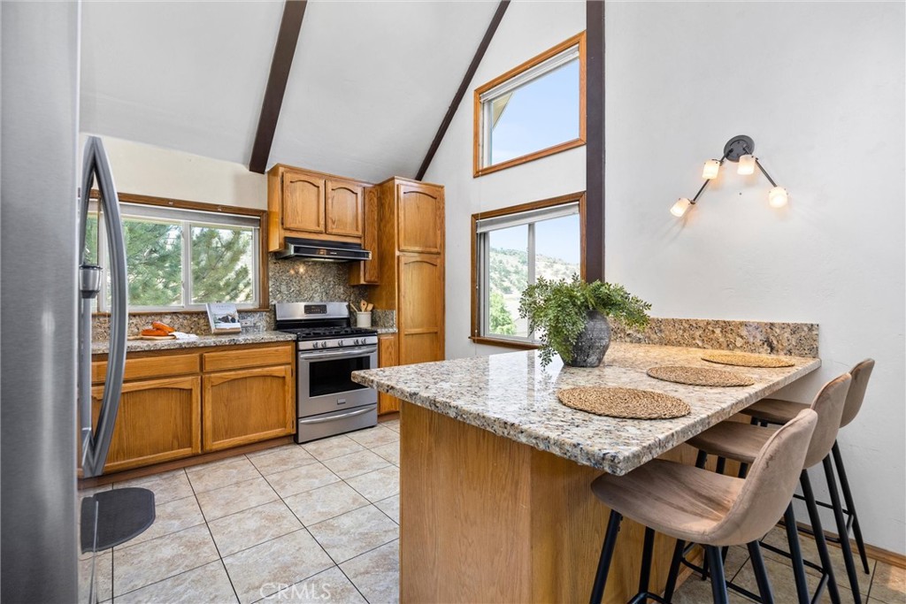 23740 Lakeview Drive Tehachapi, CA 93561 - Photo 12 of 48 a kitchen with granite countertop a table chairs stove and cabinets