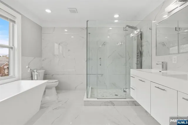 a bathroom with a bathtub shower sink vanity and toilet