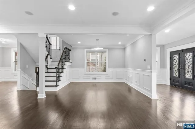 a view of an empty room with wooden floor and stairs