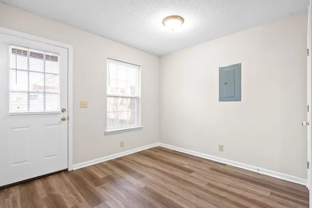 an empty room with wooden floor and windows