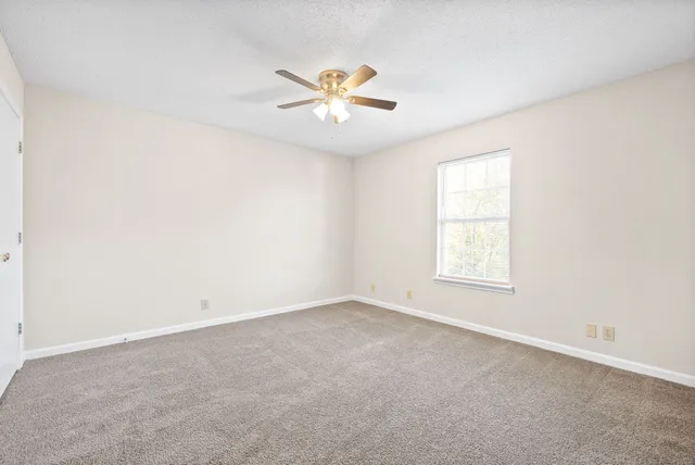 an empty room with windows and fan