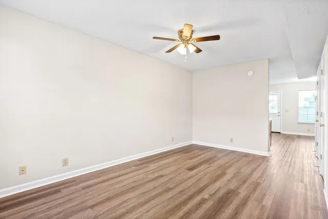 an empty room with wooden floor and windows