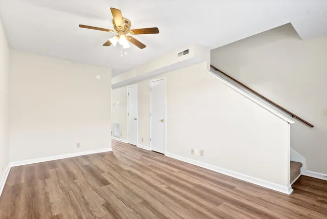 an empty room with wooden floor and fan