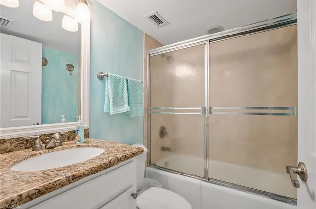 a bathroom with a granite countertop shower sink and toilet
