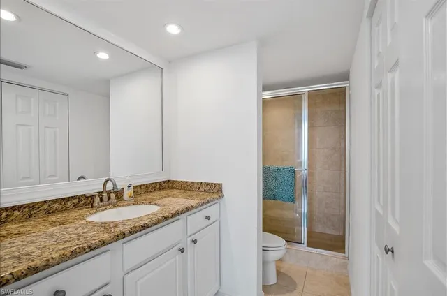a bathroom with a granite countertop sink and a toilet