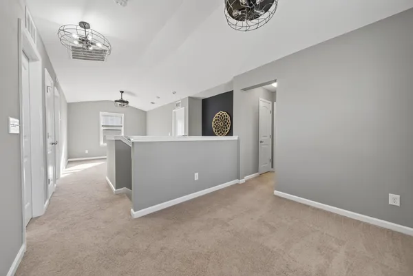 a view of a big room with windows and chandelier fan