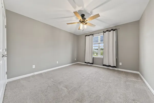 a view of an empty room with chandelier fan and fire place