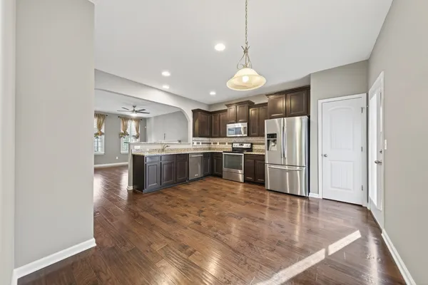 a kitchen with stainless steel appliances granite countertop a refrigerator a stove a sink dishwasher a refrigerator with a dining table and chairs
