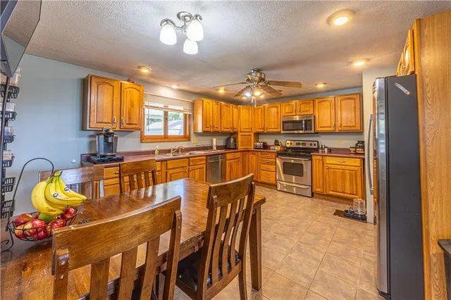 a kitchen with stainless steel appliances kitchen island granite countertop a stove top oven a sink a dining table and chairs with wooden floor