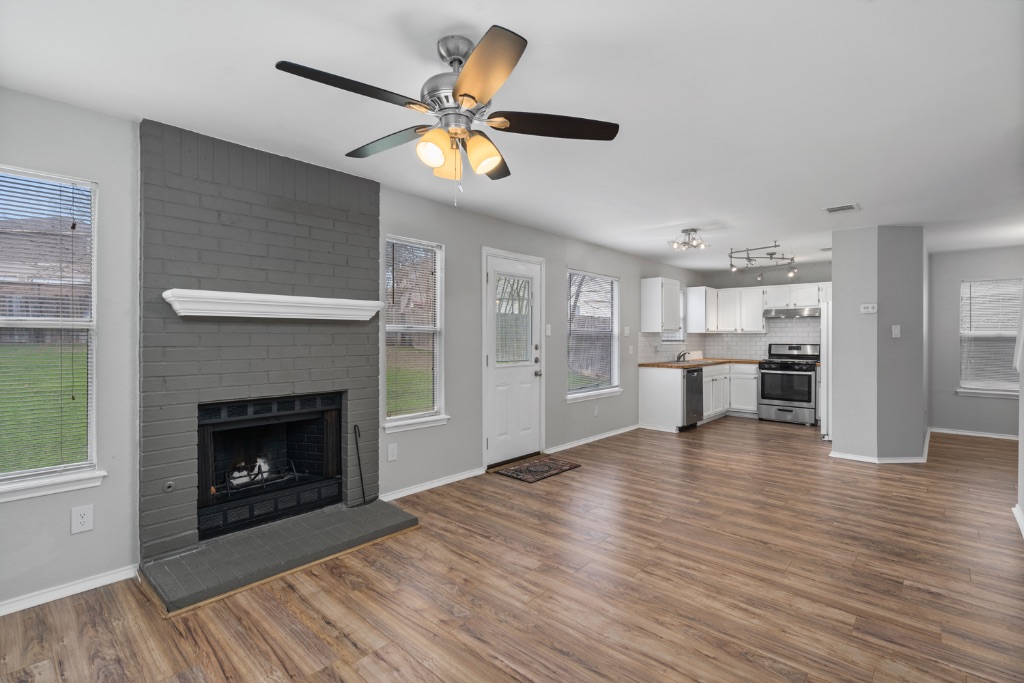 911 Flatters Way Pflugerville, TX 78660 - Photo 11 of 31 a view of an empty room with wooden floor and a kitchen