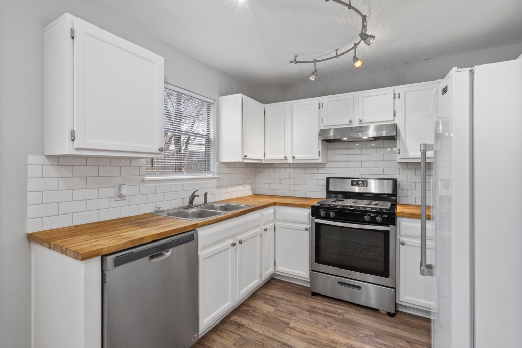 911 Flatters Way Pflugerville, TX 78660 - Photo 7 of 31 a kitchen with stainless steel appliances a sink stove and white cabinets