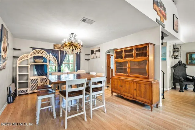a dining room with furniture a chandelier and wooden floor