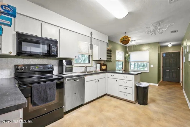 a kitchen with stainless steel appliances granite countertop a stove a sink and a microwave