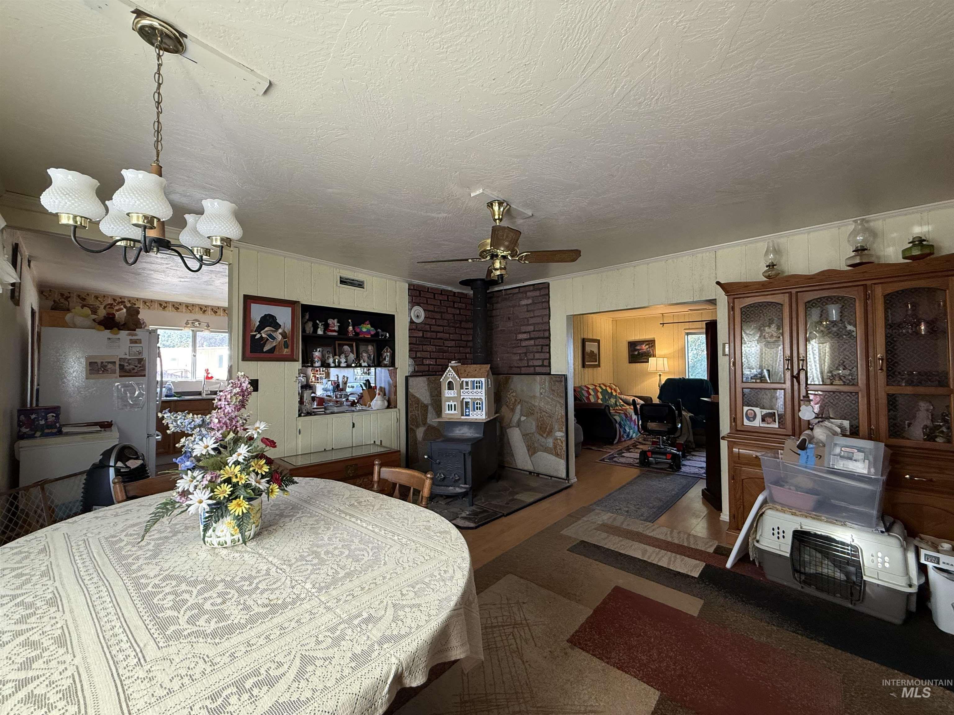 19241 West Homedale Road Caldwell, ID 83607 - Photo 25 of 35 Dining room with a wood stove, ceiling fan, hanging lights, and wooden walls