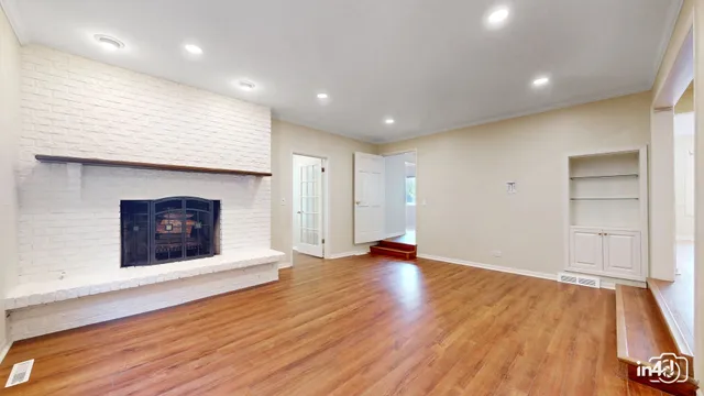 a view of an empty room with wooden floor and a fireplace