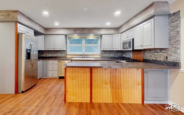 a kitchen with granite countertop wooden floors stainless steel appliances and sink