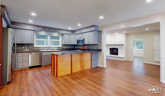 a kitchen with granite countertop a stove top oven a sink dishwasher and a refrigerator with wooden floor