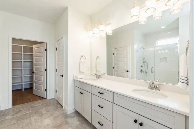 a spacious bathroom with a granite countertop sink a mirror and a shower
