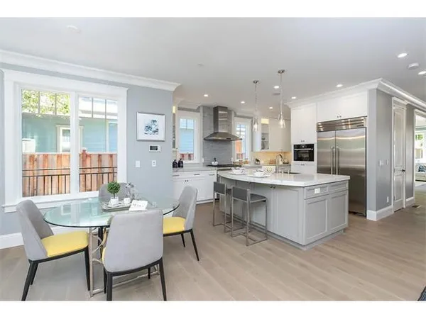 a open dining room with stainless steel appliances kitchen island granite countertop a dining table chairs and a refrigerator