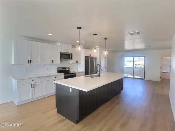 a living room with stainless steel appliances kitchen island hardwood floor and a living room view