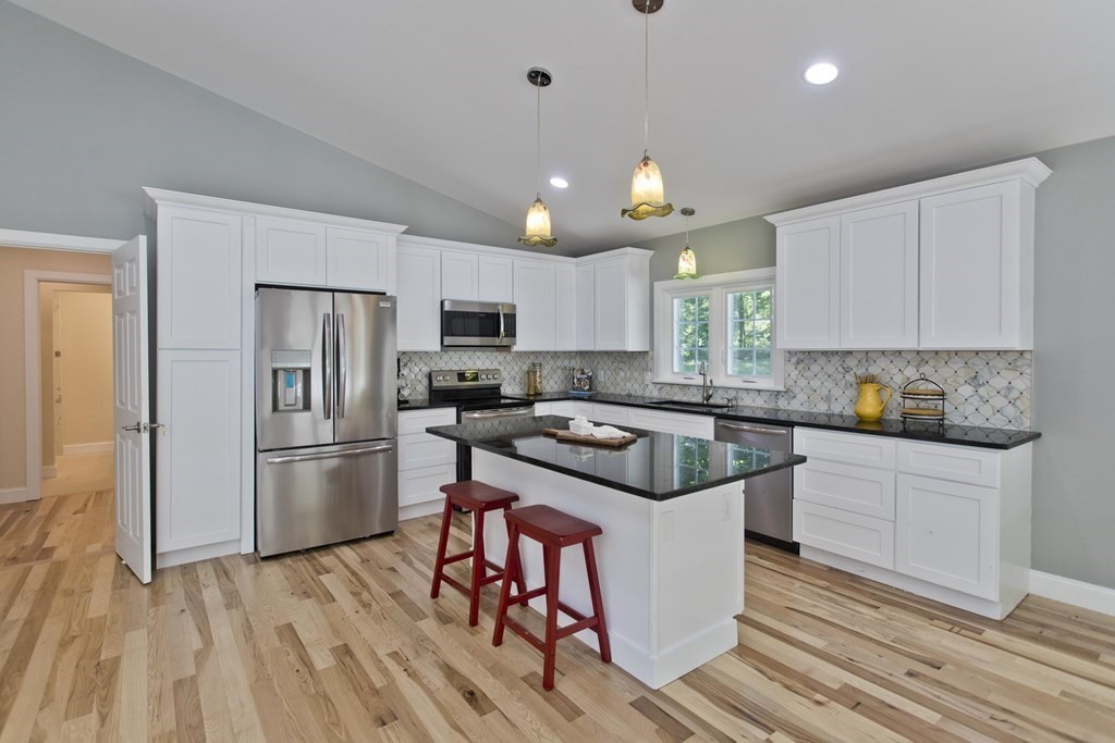 142 Harkness Road Amherst, MA 01002 - Photo 6 of 32 a kitchen with a refrigerator a sink dishwasher a stove and white cabinets with wooden floor
