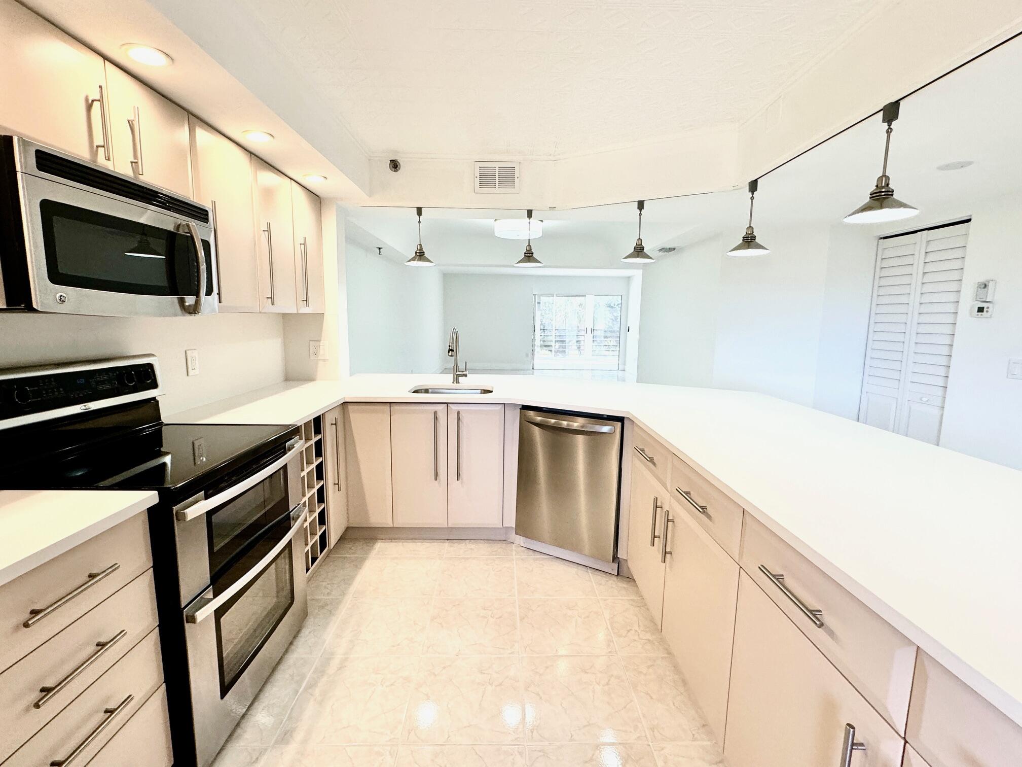 9170 Southwest 14th Street, Unit 4405 Boca Raton, FL 33428 - Photo 3 of 48 a kitchen with stainless steel appliances kitchen island granite countertop a sink a stove top oven and white cabinets