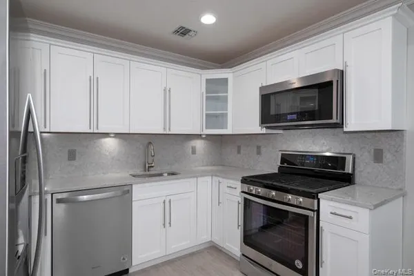 a kitchen with white cabinets and stainless steel appliances