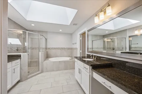 a large white bathroom with a granite countertop sink mirror and bathtub
