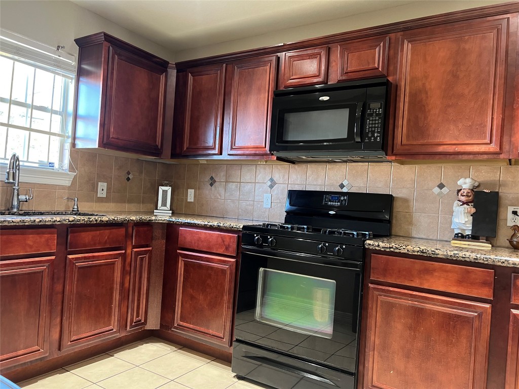 10902 Seneca Street Houston, TX 77016 - Photo 3 of 14 a kitchen with granite countertop a stove top oven microwave and cabinets