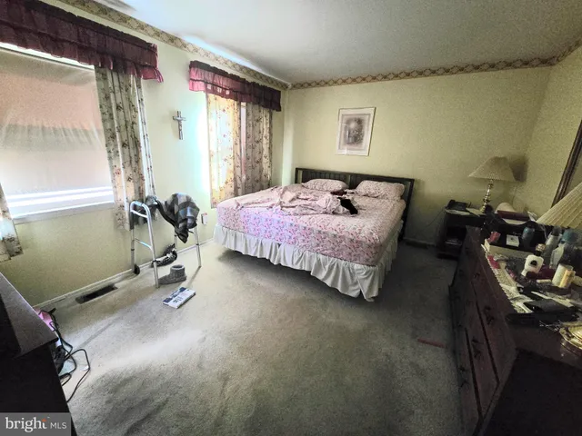a bedroom with a bed and a dresser next to a window