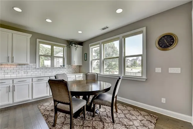 a kitchen with kitchen island granite countertop a stove a sink a refrigerator and a dining table with wooden floor