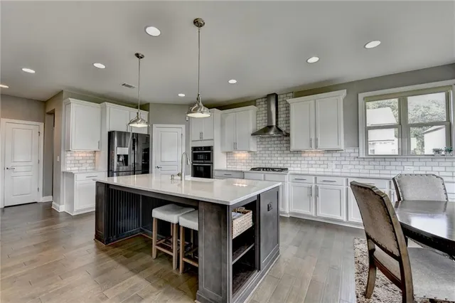 a kitchen with stainless steel appliances granite countertop a table chairs refrigerator and microwave