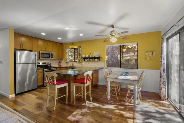 a kitchen with stainless steel appliances kitchen island granite countertop table chairs and a refrigerator